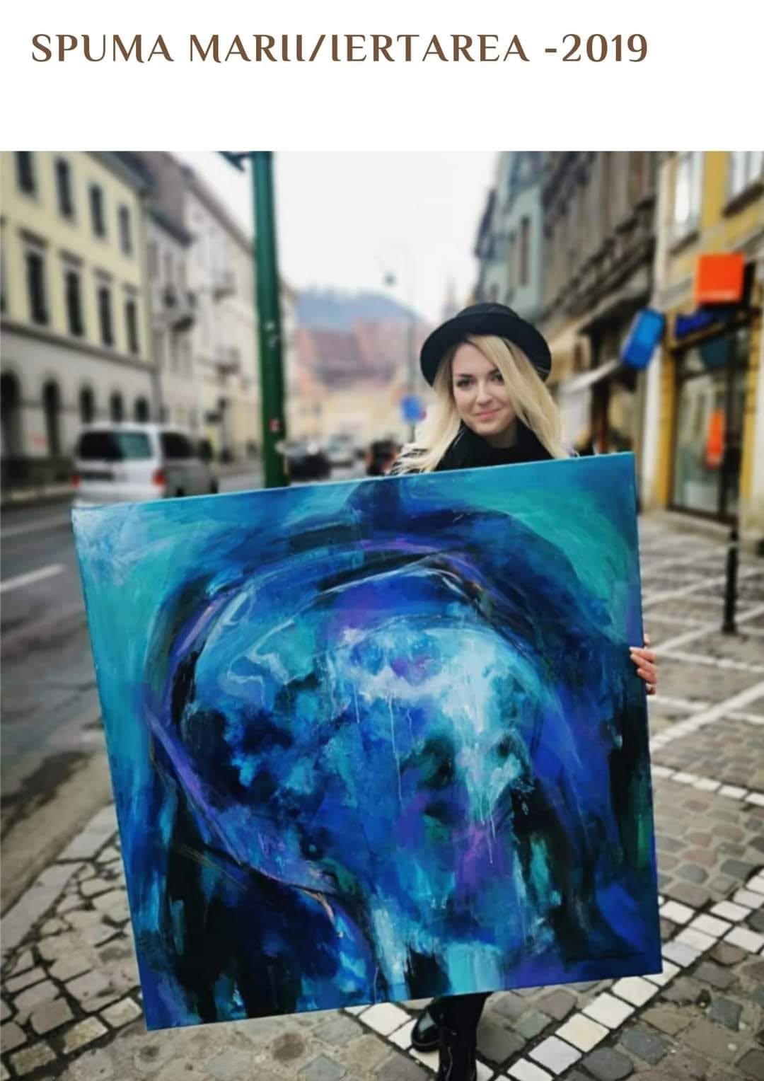 Artista ținând lucrarea Spuma mării / Iertarea, în tonuri de albastru și turcoaz.